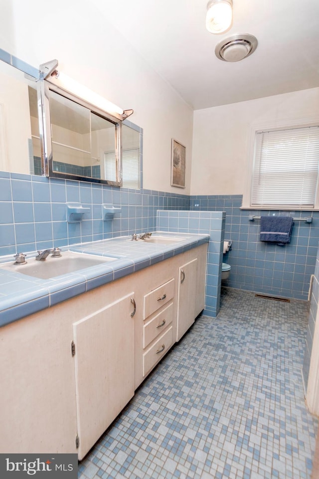 bathroom featuring vanity and tile walls