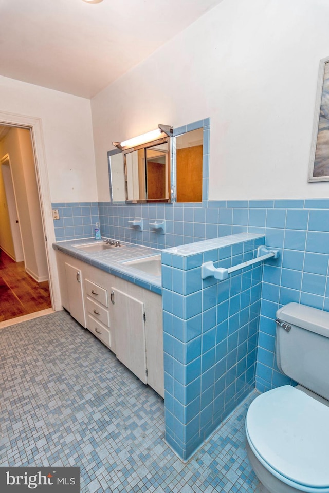 bathroom featuring tile walls, a wainscoted wall, vanity, and toilet