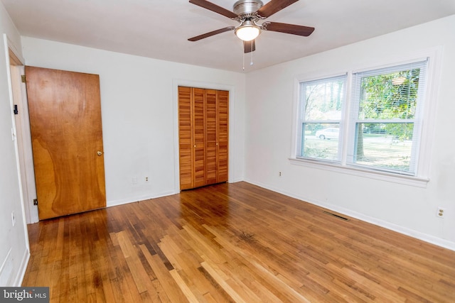 unfurnished bedroom featuring baseboards, wood finished floors, visible vents, and a closet