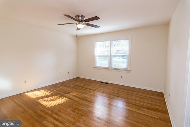 spare room featuring ceiling fan, baseboards, wood finished floors, and visible vents