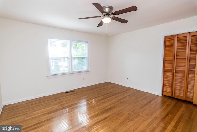 unfurnished bedroom featuring hardwood / wood-style floors, ceiling fan, and a closet