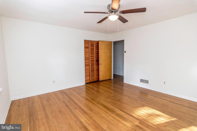 empty room featuring baseboards, a ceiling fan, visible vents, and light wood-type flooring