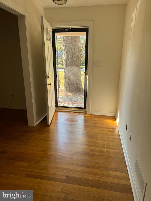 doorway to outside featuring baseboards, wood finished floors, and visible vents
