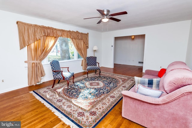 living area with ceiling fan, baseboards, and wood finished floors