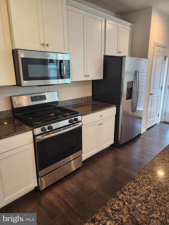 kitchen featuring dark stone countertops, appliances with stainless steel finishes, dark hardwood / wood-style floors, and white cabinetry