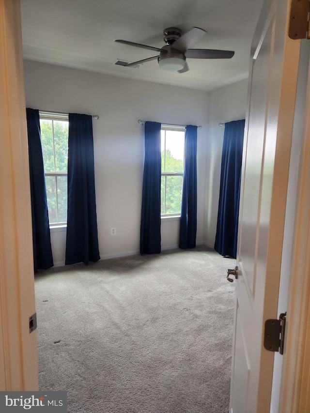 carpeted spare room with ceiling fan and a wealth of natural light