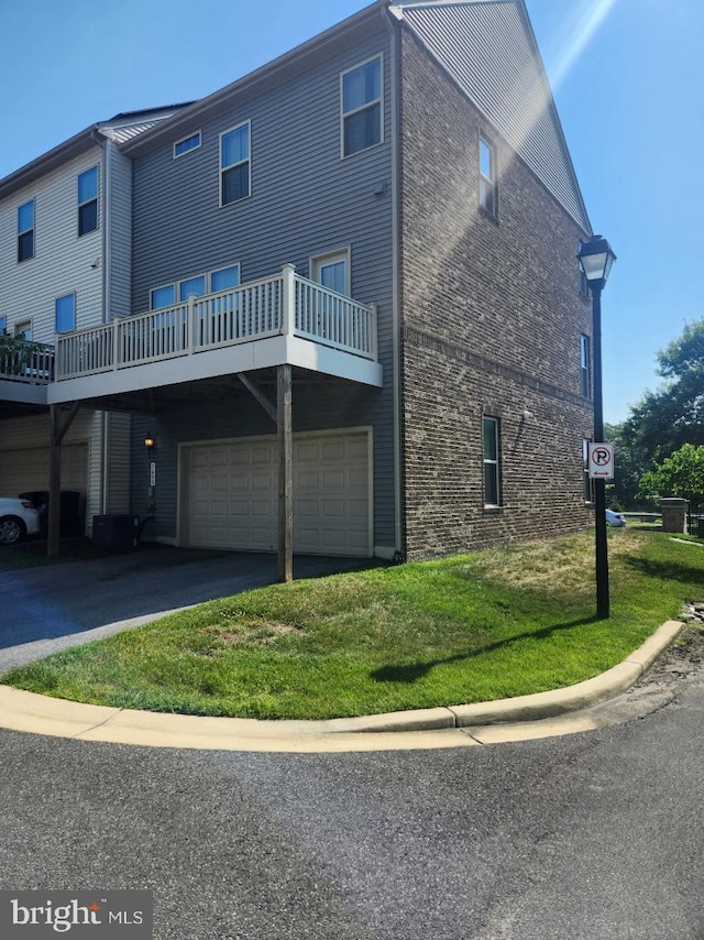 back of house with a garage, a deck, and a lawn