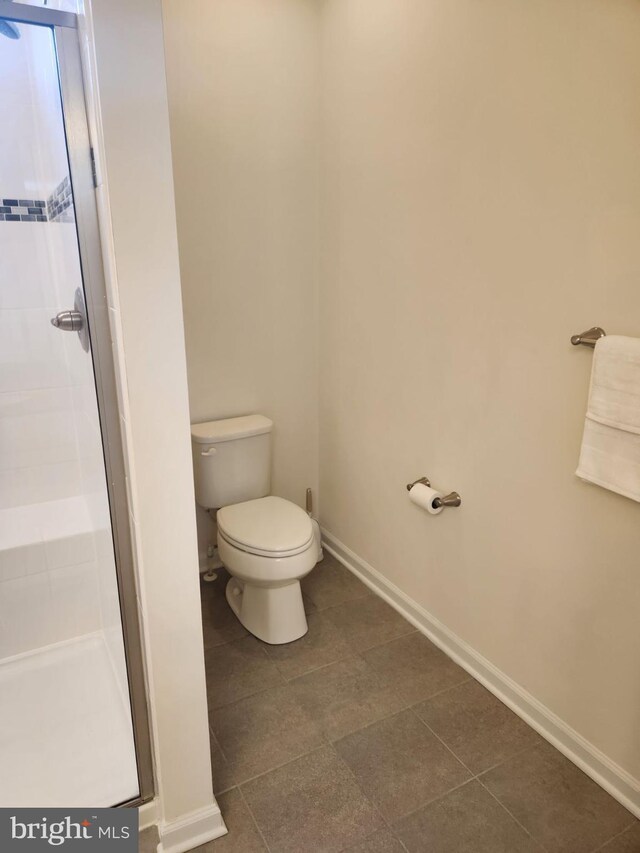 bathroom with an enclosed shower, tile patterned floors, and toilet