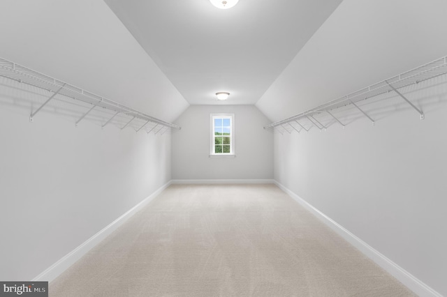 spacious closet with lofted ceiling and light carpet