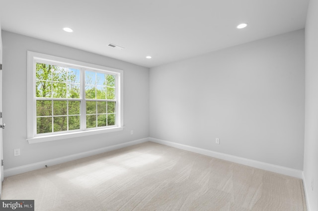 spare room featuring light carpet, recessed lighting, visible vents, and baseboards