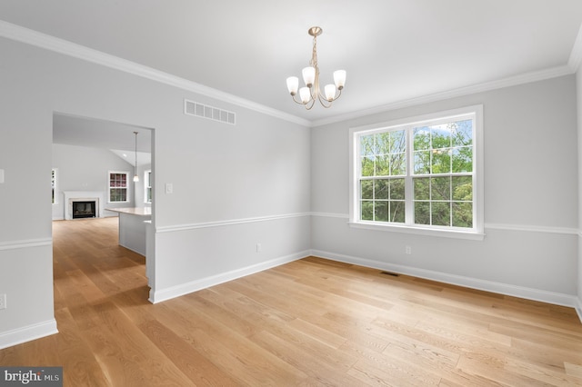 unfurnished room with a notable chandelier, a fireplace, visible vents, light wood-type flooring, and crown molding