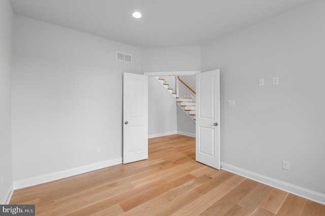 unfurnished room featuring light wood-type flooring, baseboards, and visible vents