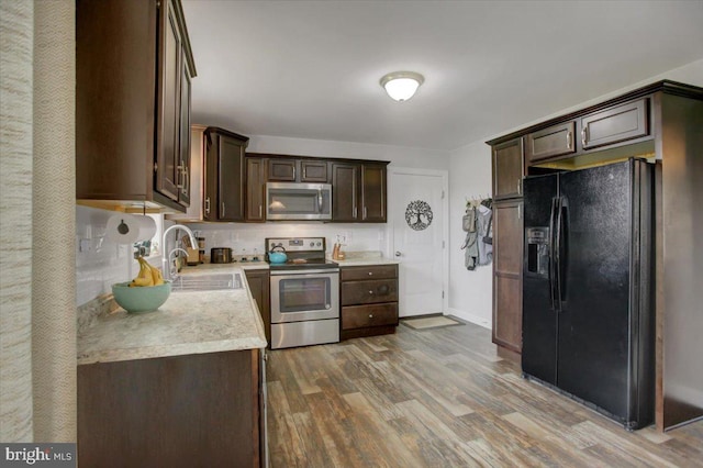 kitchen featuring wood-type flooring, appliances with stainless steel finishes, sink, and dark brown cabinetry