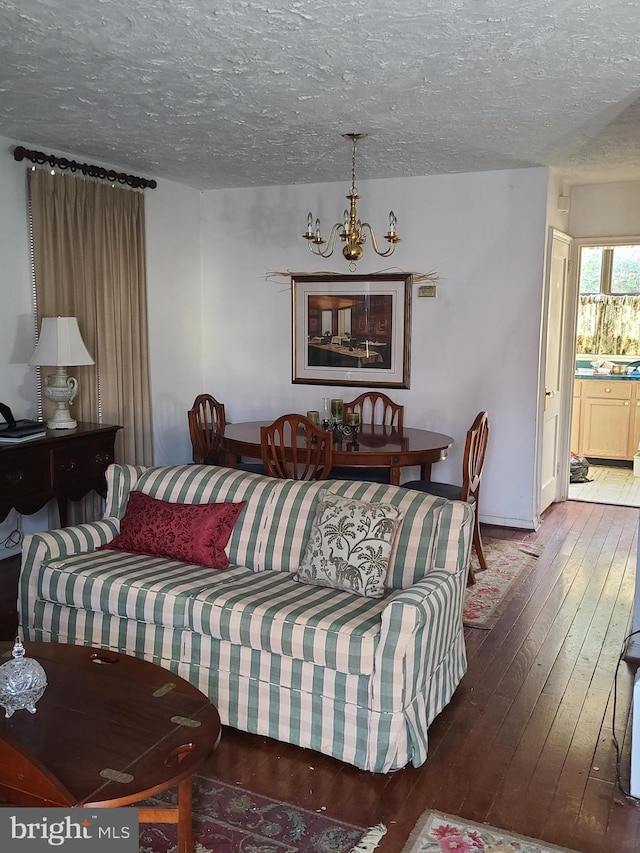 living room with hardwood / wood-style floors, a notable chandelier, and a textured ceiling