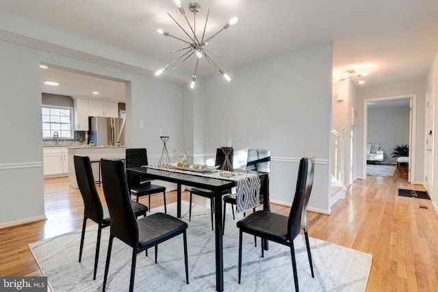 dining room featuring sink, a chandelier, and light wood-type flooring