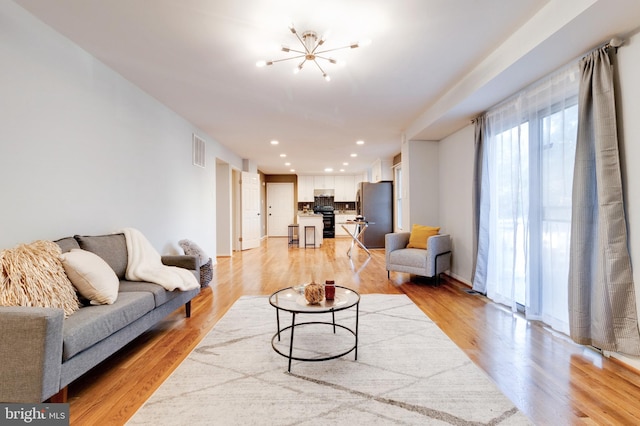 living room featuring a notable chandelier and light wood-type flooring