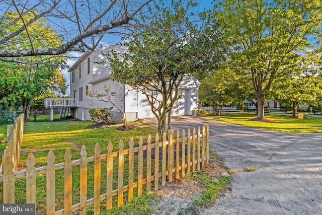 view of side of property with a wooden deck, a garage, and a lawn