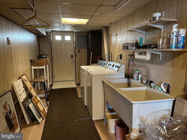 laundry area with hardwood / wood-style floors, sink, wooden walls, and independent washer and dryer