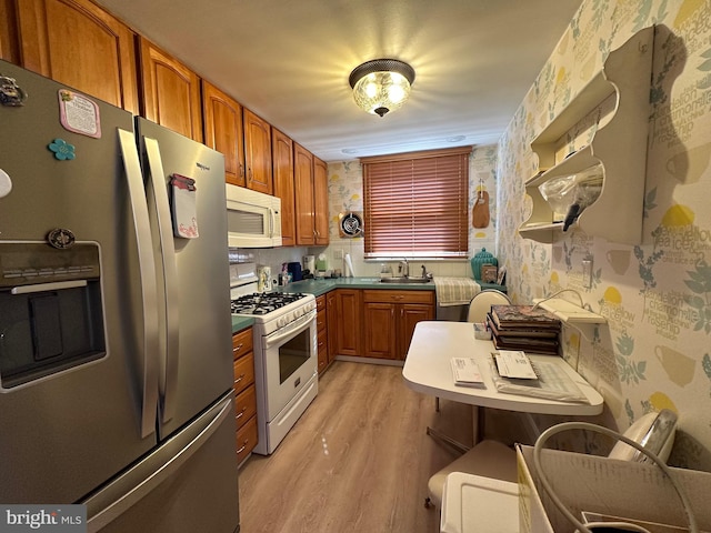 kitchen featuring white appliances, sink, and light wood-type flooring