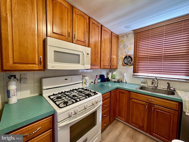 kitchen featuring white appliances, light hardwood / wood-style flooring, sink, and backsplash