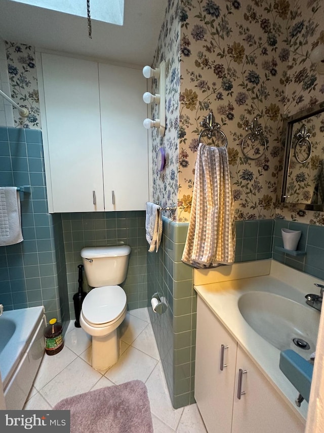 full bathroom featuring toilet, a skylight, vanity, and tile walls