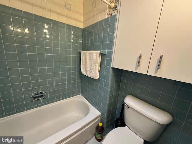 bathroom featuring toilet, tiled shower / bath combo, and tile walls