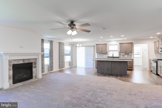 unfurnished living room featuring carpet flooring, ceiling fan with notable chandelier, and sink