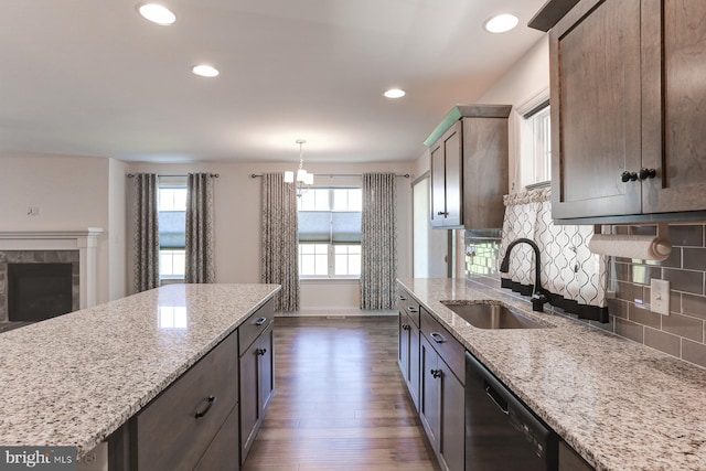 kitchen featuring backsplash, light stone countertops, sink, and black dishwasher