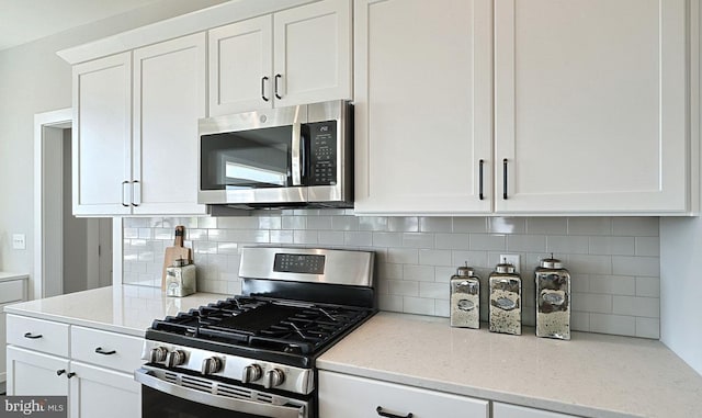 kitchen featuring backsplash, light stone countertops, white cabinetry, and stainless steel appliances