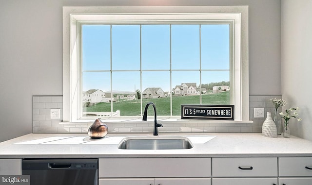 kitchen featuring stainless steel dishwasher, backsplash, light stone counters, and sink