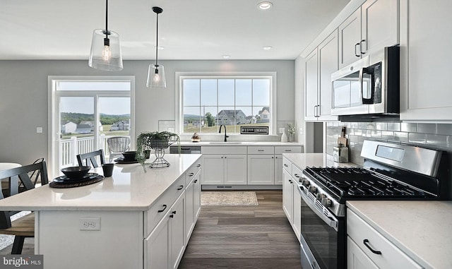 kitchen with a kitchen breakfast bar, a wealth of natural light, appliances with stainless steel finishes, a kitchen island, and white cabinetry