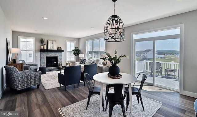 dining area with plenty of natural light, a stone fireplace, and dark hardwood / wood-style flooring