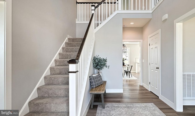 stairs featuring a towering ceiling and hardwood / wood-style flooring