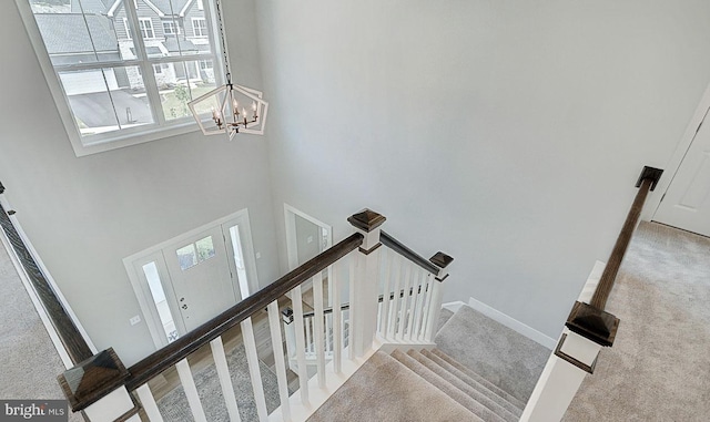 staircase featuring carpet flooring, a chandelier, and a high ceiling