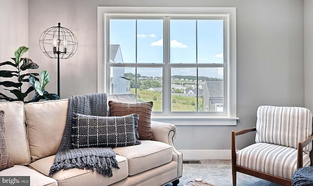 sitting room with carpet flooring, a wealth of natural light, and a chandelier