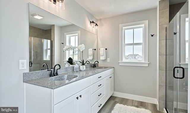 bathroom featuring wood-type flooring, vanity, a shower with door, and a healthy amount of sunlight