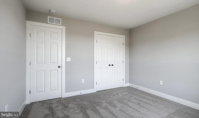 unfurnished bedroom with a closet and dark carpet