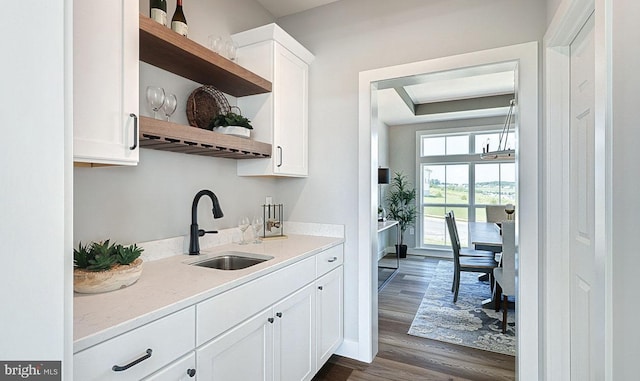 bar featuring light stone counters, dark hardwood / wood-style flooring, white cabinetry, and sink