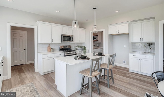 kitchen with pendant lighting, backsplash, white cabinetry, and stainless steel appliances