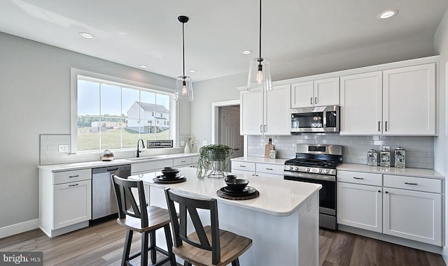 kitchen featuring sink, hanging light fixtures, a kitchen breakfast bar, white cabinets, and appliances with stainless steel finishes