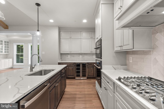 kitchen featuring custom exhaust hood, white cabinetry, sink, and stainless steel appliances