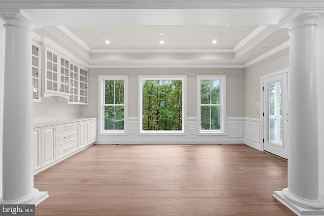 unfurnished living room with crown molding, a raised ceiling, and light wood-type flooring