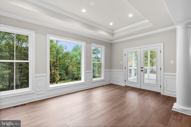 doorway with hardwood / wood-style floors, ornate columns, a healthy amount of sunlight, and french doors