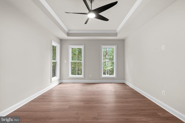 empty room featuring crown molding, hardwood / wood-style floors, a tray ceiling, and ceiling fan