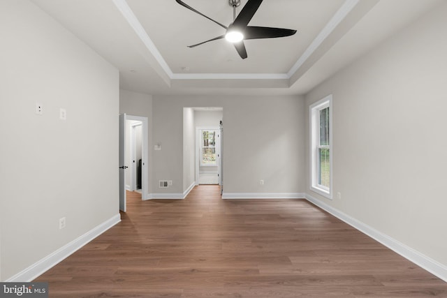 empty room featuring hardwood / wood-style floors, a healthy amount of sunlight, and a raised ceiling