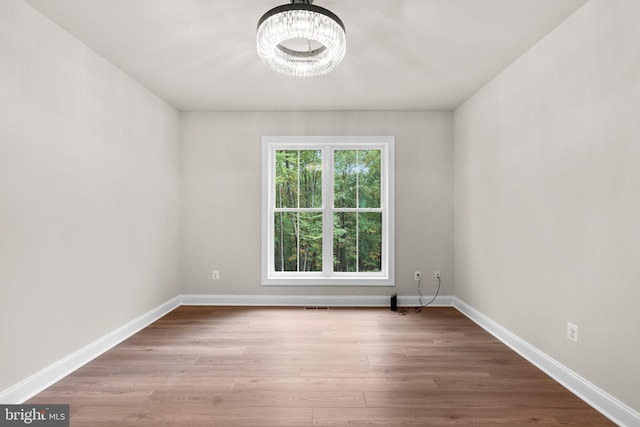 spare room featuring light hardwood / wood-style floors and an inviting chandelier