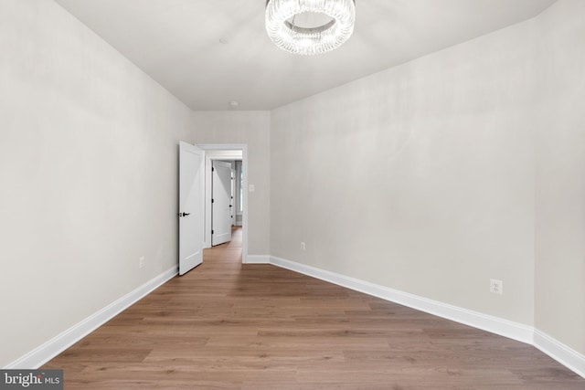 unfurnished room with light hardwood / wood-style flooring and a chandelier