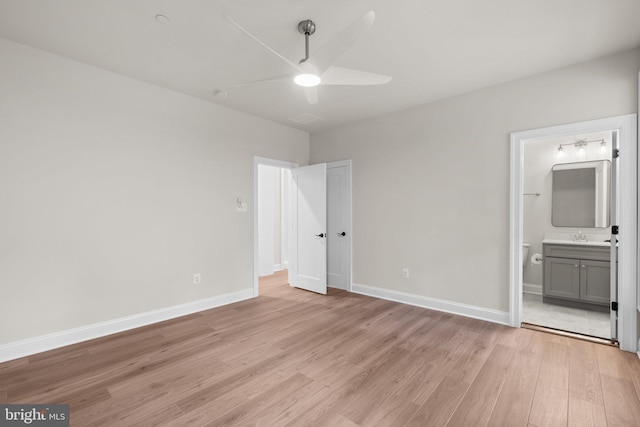 unfurnished bedroom featuring light hardwood / wood-style flooring, ensuite bathroom, sink, and ceiling fan