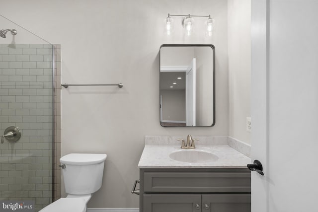 bathroom with vanity, a tile shower, and toilet