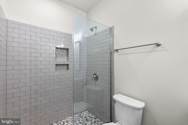 bathroom featuring toilet and a shower with shower door